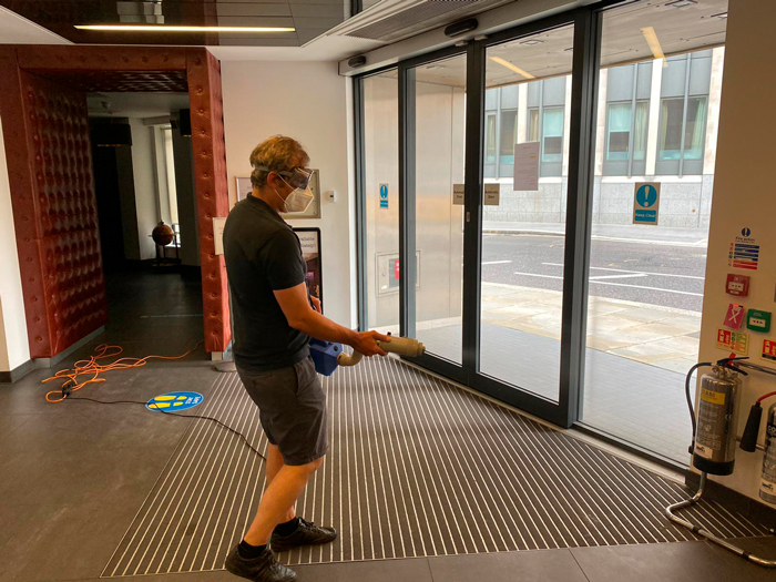 Man using disinfection spray in building entrance