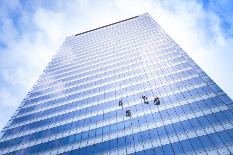 tall building with windows cleaners on ropes