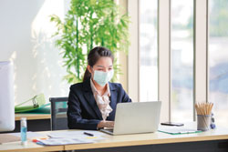 Office worker at desk with face mask on