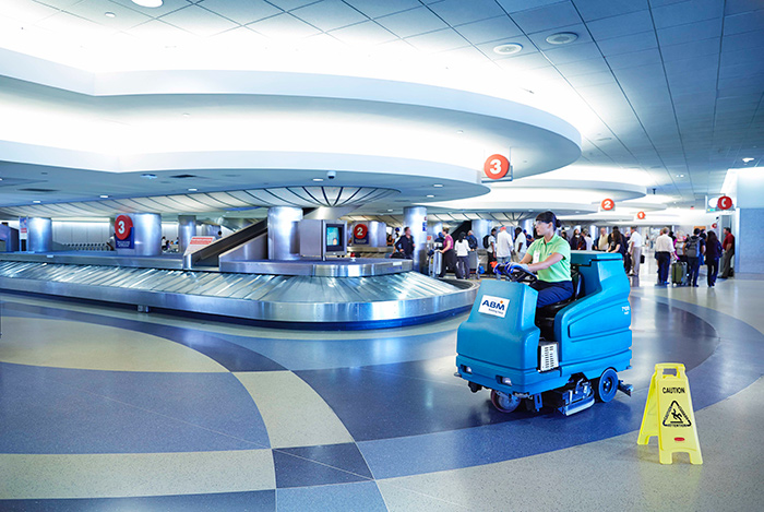 ABM UK staff member on a ride-along floor cleaner at an airport terminal