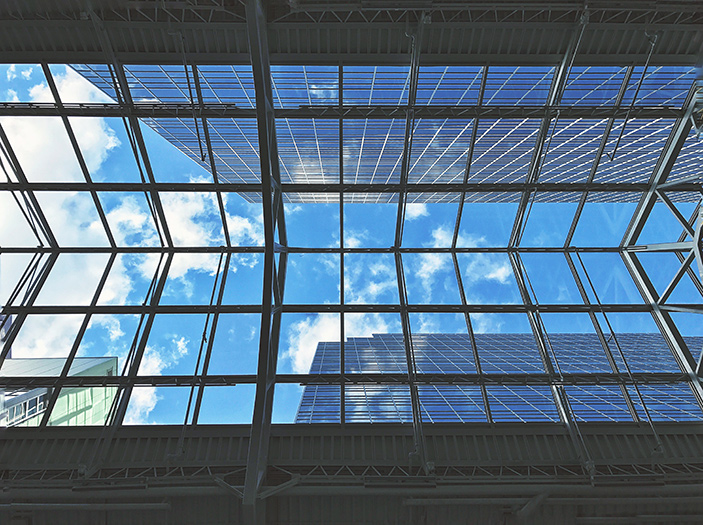 Looking up through a glass roof to blue sky