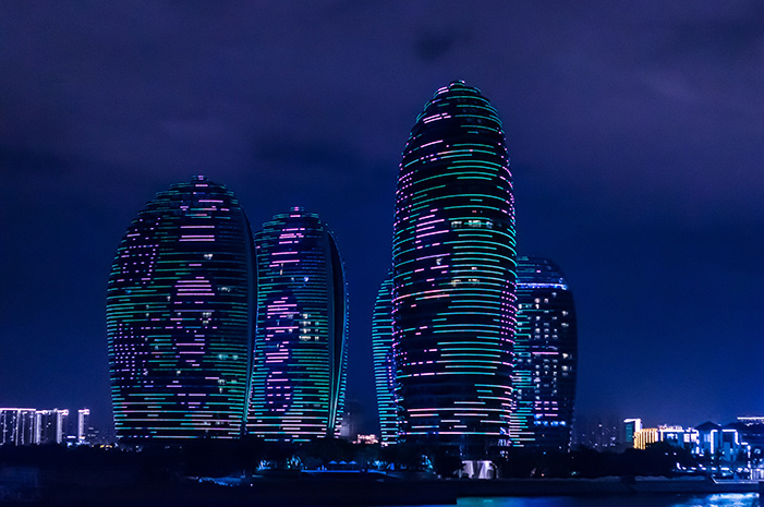 Three neon-lit buildings in the night sky