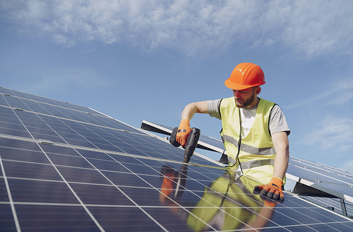 A solar panel installation with the worker wearing PPE