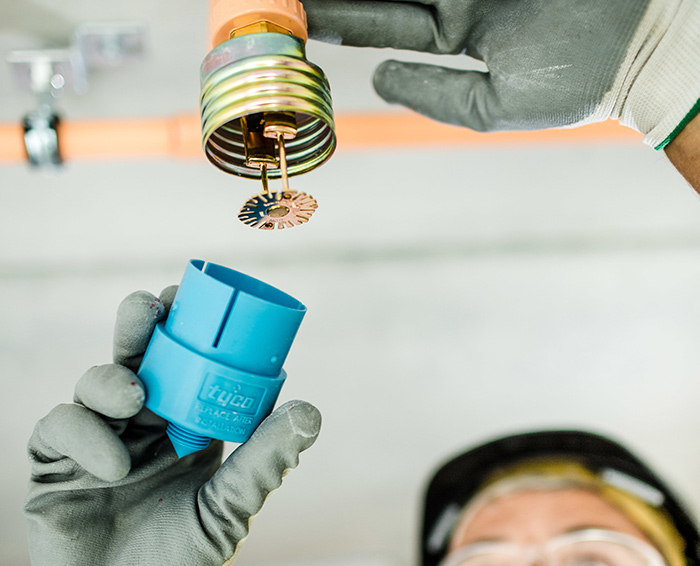 A PTSG's technician's hands working on a fire sprinkler