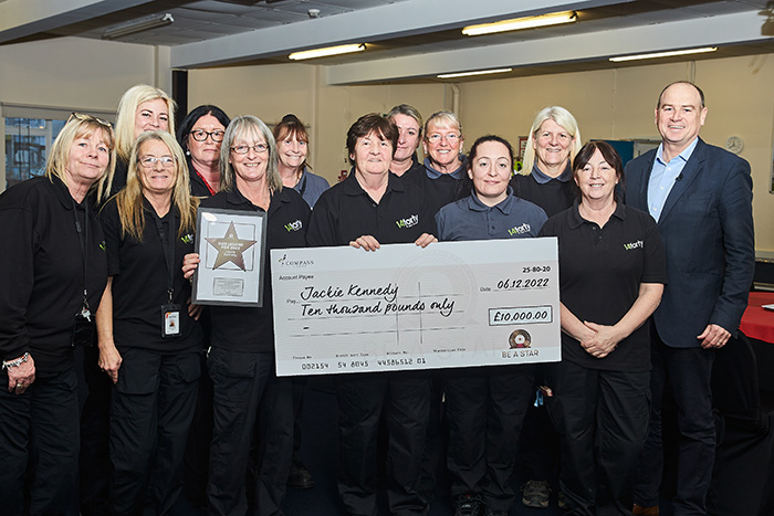 Jackie with her cheque surrounded by her team of cleaners