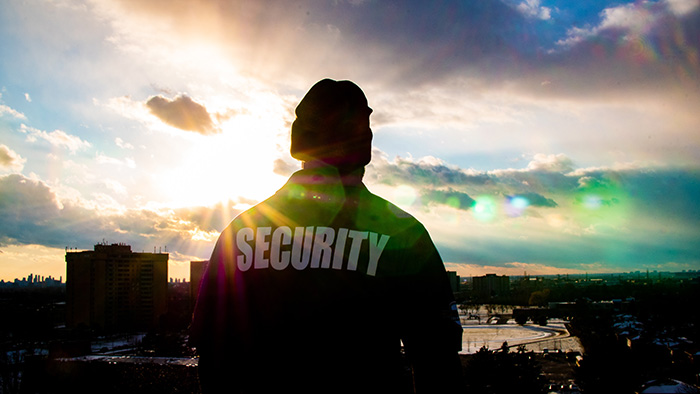 A security officer silhouetted against a dramatic sunset