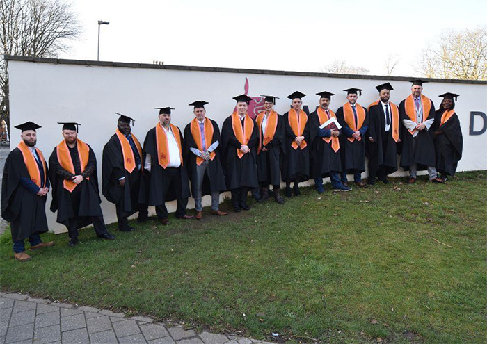The graduates stood on grass outside De Montford University