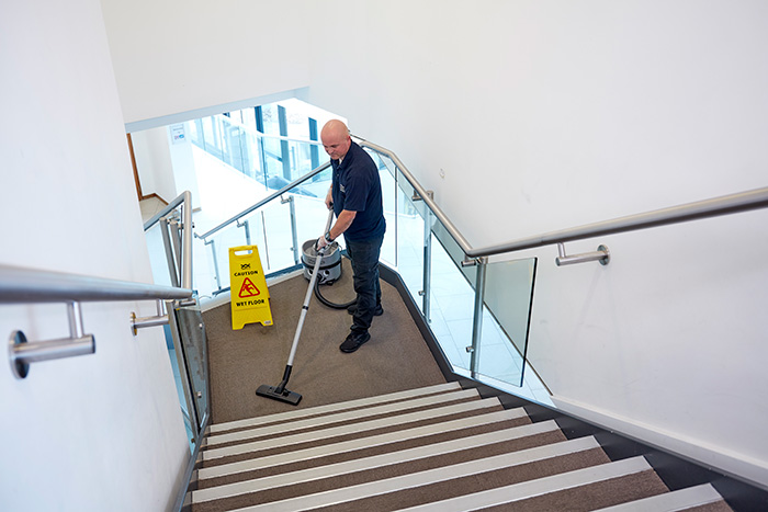 A cleaning vacuuming stairs